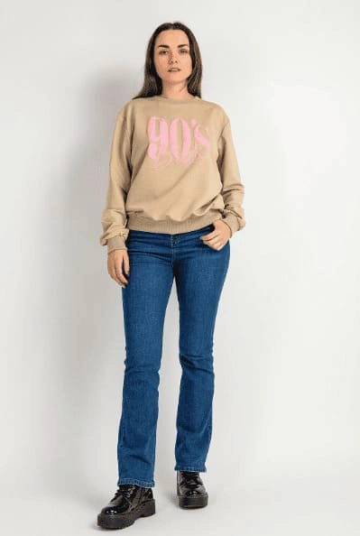 Kobieta w jeansach, cielistej bluzie i czarnych butach