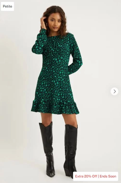 Kobieta w rozmiarze petite w zielono-czarnej sukience i czarnych kozakach do kolan