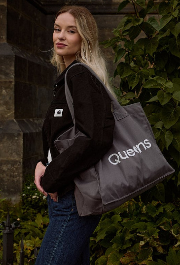 Blondynka w czarnej bluzie i dużej shopperce z nazwą sklepu