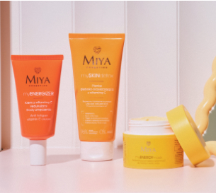 Pomarańczowe tubki z kosmetykami i żółty krem w odkręconym pojemniczku