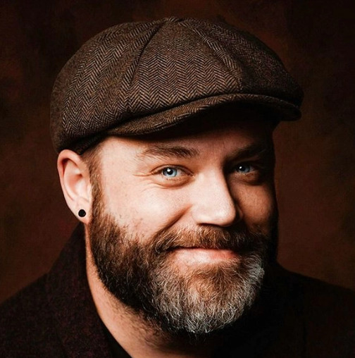 Brodaty mężczyzna w brązowym kaszkiecie i z kolczykiem