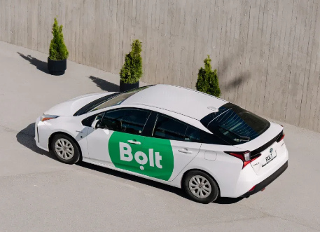 Biały samochód z zielonym logo w betonowej przestrzeni