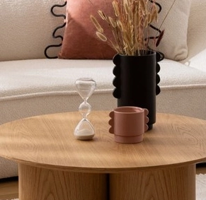 Drewniany stolik kawowy z czarnym wazonem, kubkiem i kleppsydrą