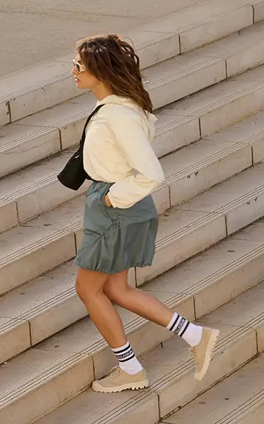 Kobieta z jasnych butach i spódnicy wchodząca po schodach