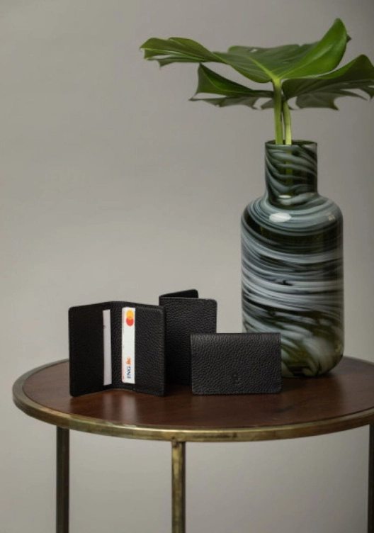 Skórzany portfel na małym stoliku obok wazonu z kwiatem