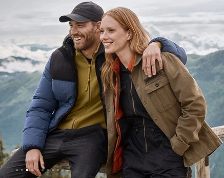 Uśmiechnięci kobieta i mężczyzna w sportowych ubraniach na tle gór