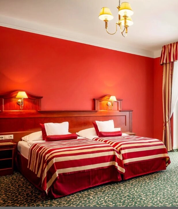 Pokój hotelowy z czerwonymi ścianami i pościelą w czerwono-białe paski