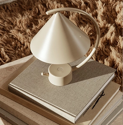 Biała lampka biurkowa w kształcie stożka na książkach